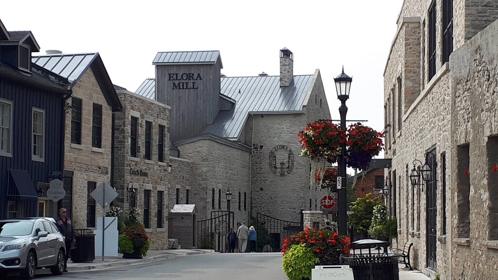 downtown streets of elora ontario, with the front view of the elora mill and several hanging planters of flowers on the opposite side of the street