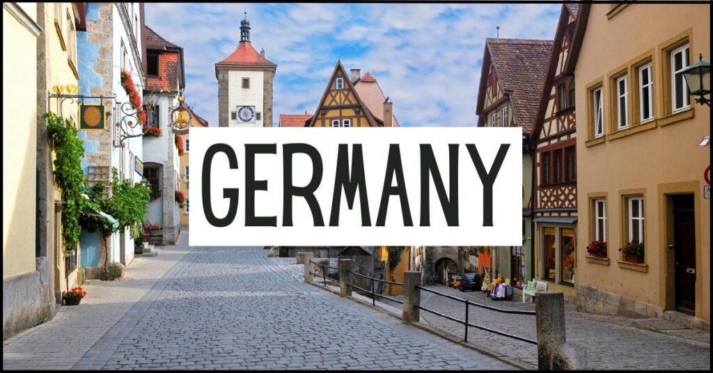 Cobblestone street lined with colorful half timbered houses and a medieval clock tower in Rothenburg ob der Tauber. Large white text overlay reads "GERMANY".